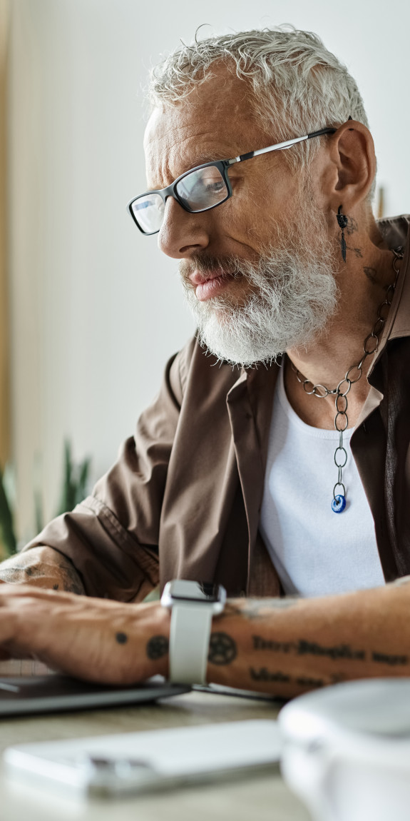 Man with white hair using a laptop at a table