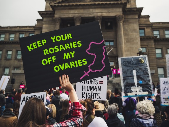 Protester holding sign reading Keep you rosaries off my ovaries