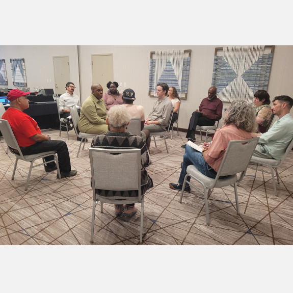 12 people sitting in a circle in a conference room