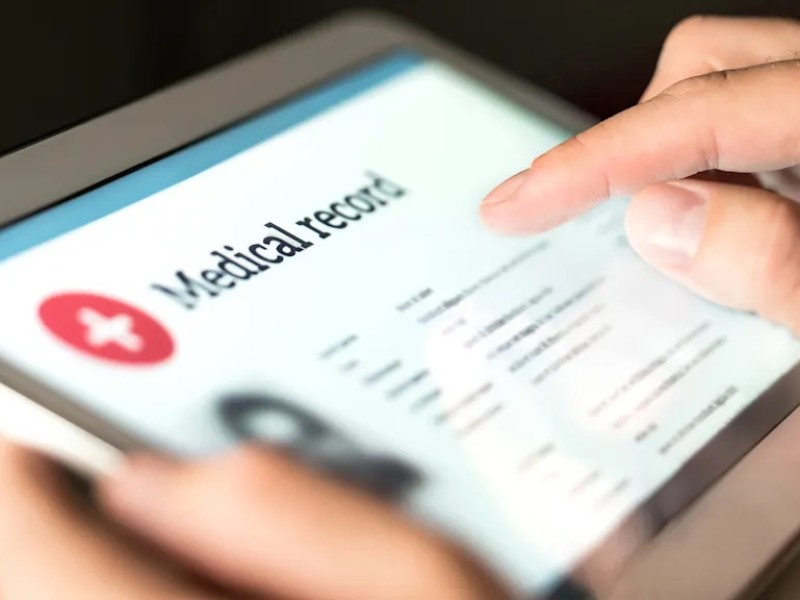 iPad reading medical record held by white person's hands.