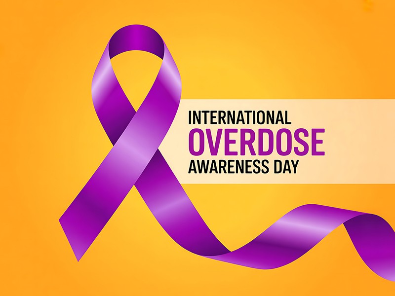 Gold background with purple ribbon reading International Overdose Awareness Day