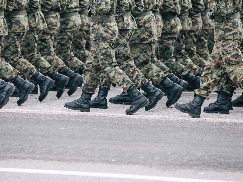 legs of soldiers in camo marching in lines on a street.