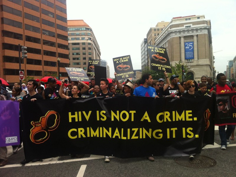 Marchers Holding a banner reading HIV is Not a Crime. Criminalizing it is.