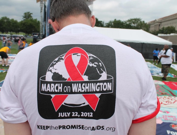 The back of a white man wearing a March on Washington tee and standing at the AIDS Quilt on the Mall in Washington DC. Photo by Elvert Barnes via Flickr