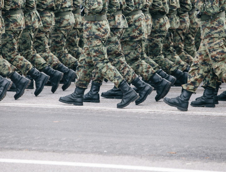 legs of soldiers in camo marching in lines on a street.