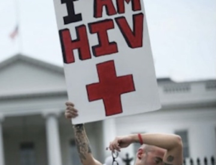 White man in front of White House holding sign reading I Am HIV+