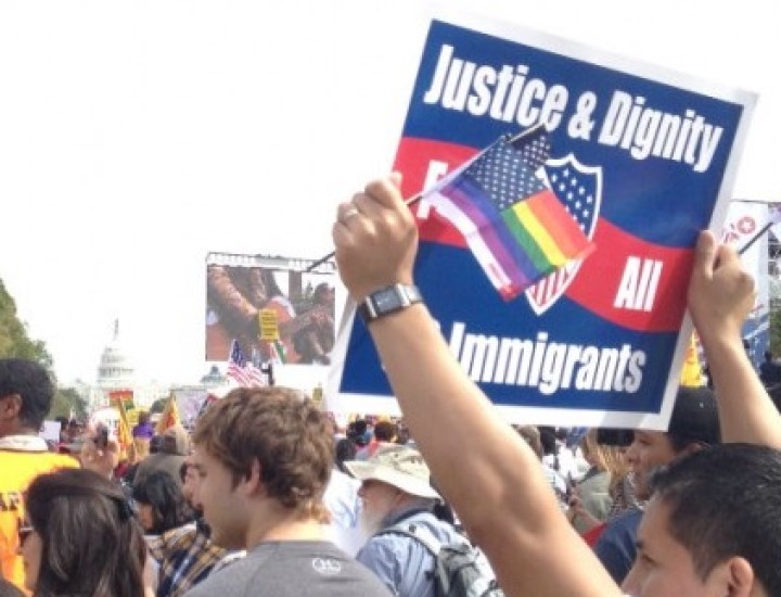 Protester in a crowd holding sing that says Justice & Dignity for all Immigrants