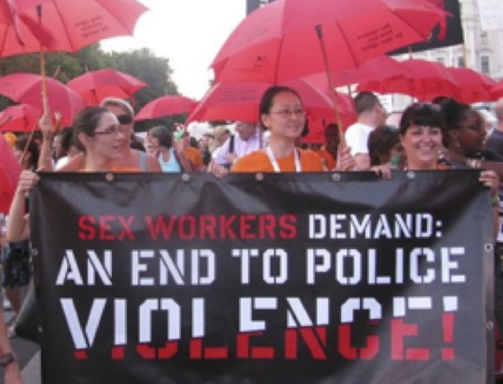 Women with Red Umbrellas marching with Banner Reading Sex Workers Demand and End to Police Violence