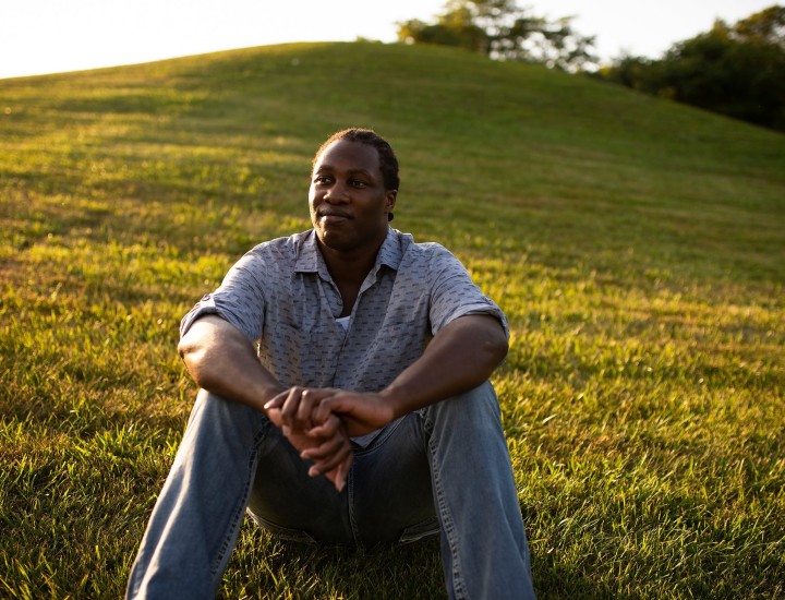 Michael Johnson sitting outside in a field of grass.
